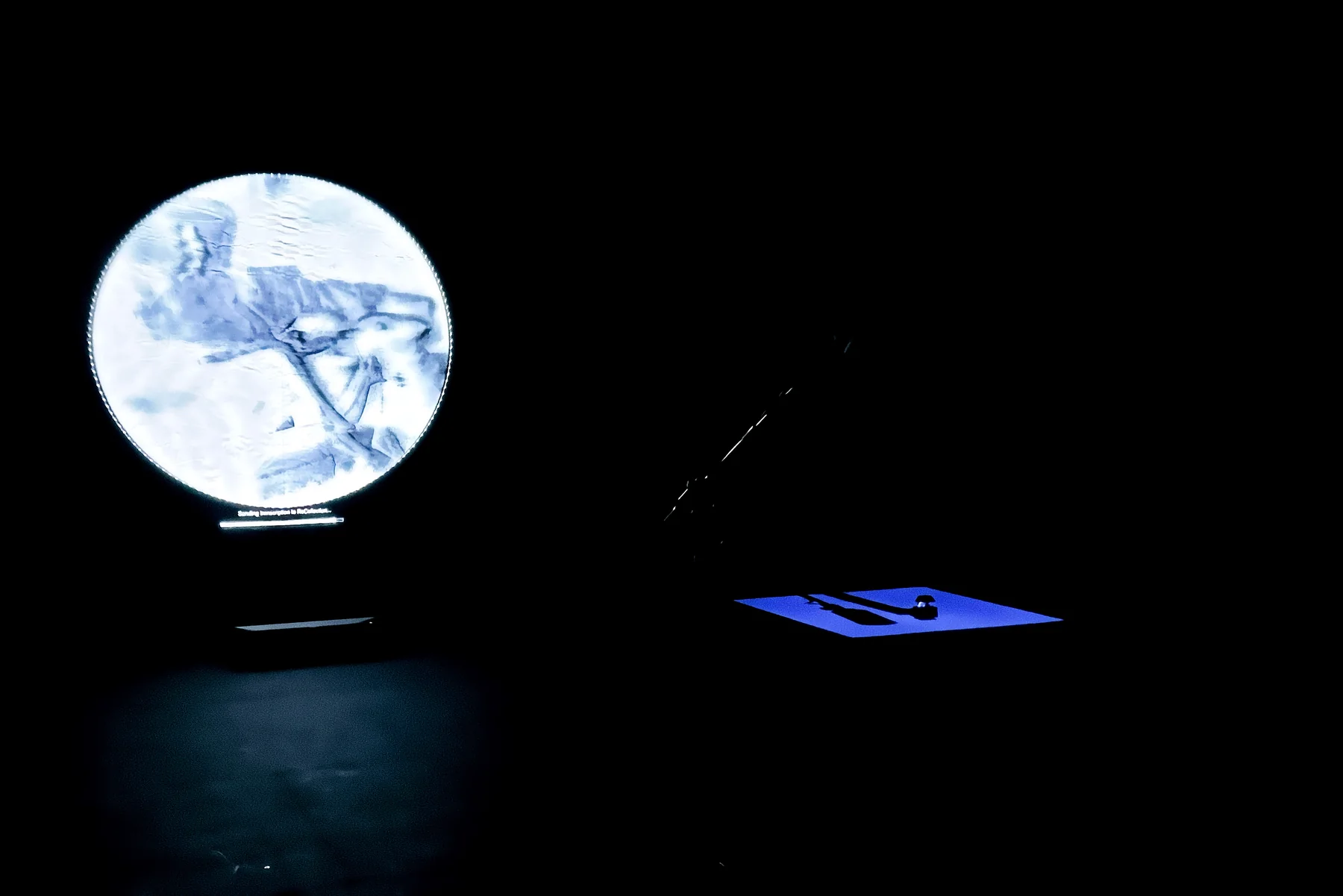 The circular image and a low plinth in a dark exhibition room